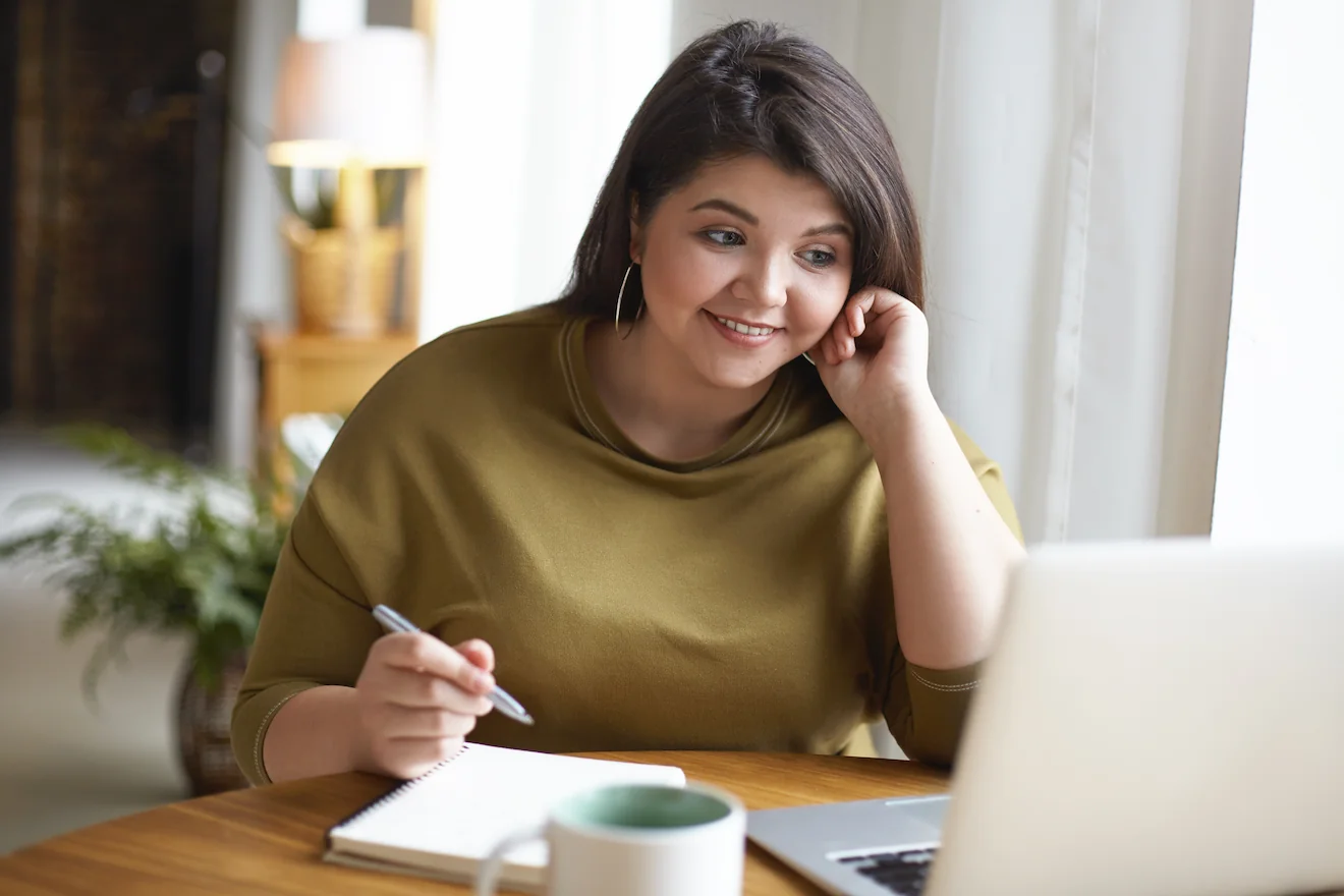 Hopeful plus size woman looking at computer screen